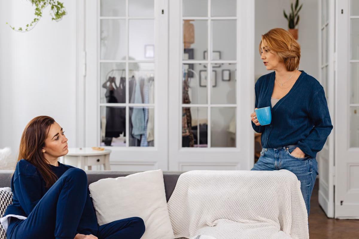 Two women in a cozy home setting having a casual conversation over coffee.